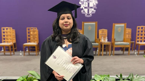 Prachi is standing up and holding her degree certificate